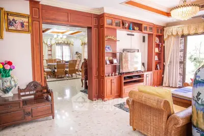Elegant living room with wooden furniture and open layout to dining area, featuring a cozy ambiance.