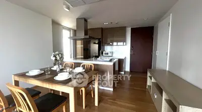 Modern kitchen with dining area featuring wooden furniture and sleek appliances.
