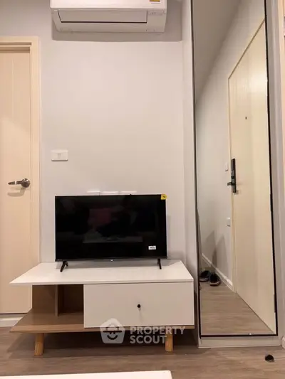 Modern living room with sleek TV stand and mirrored wardrobe, showcasing minimalist design and efficient use of space.