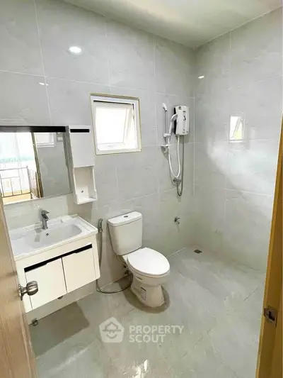 Modern bathroom with sleek fixtures and wall-mounted shower in a bright, tiled space.