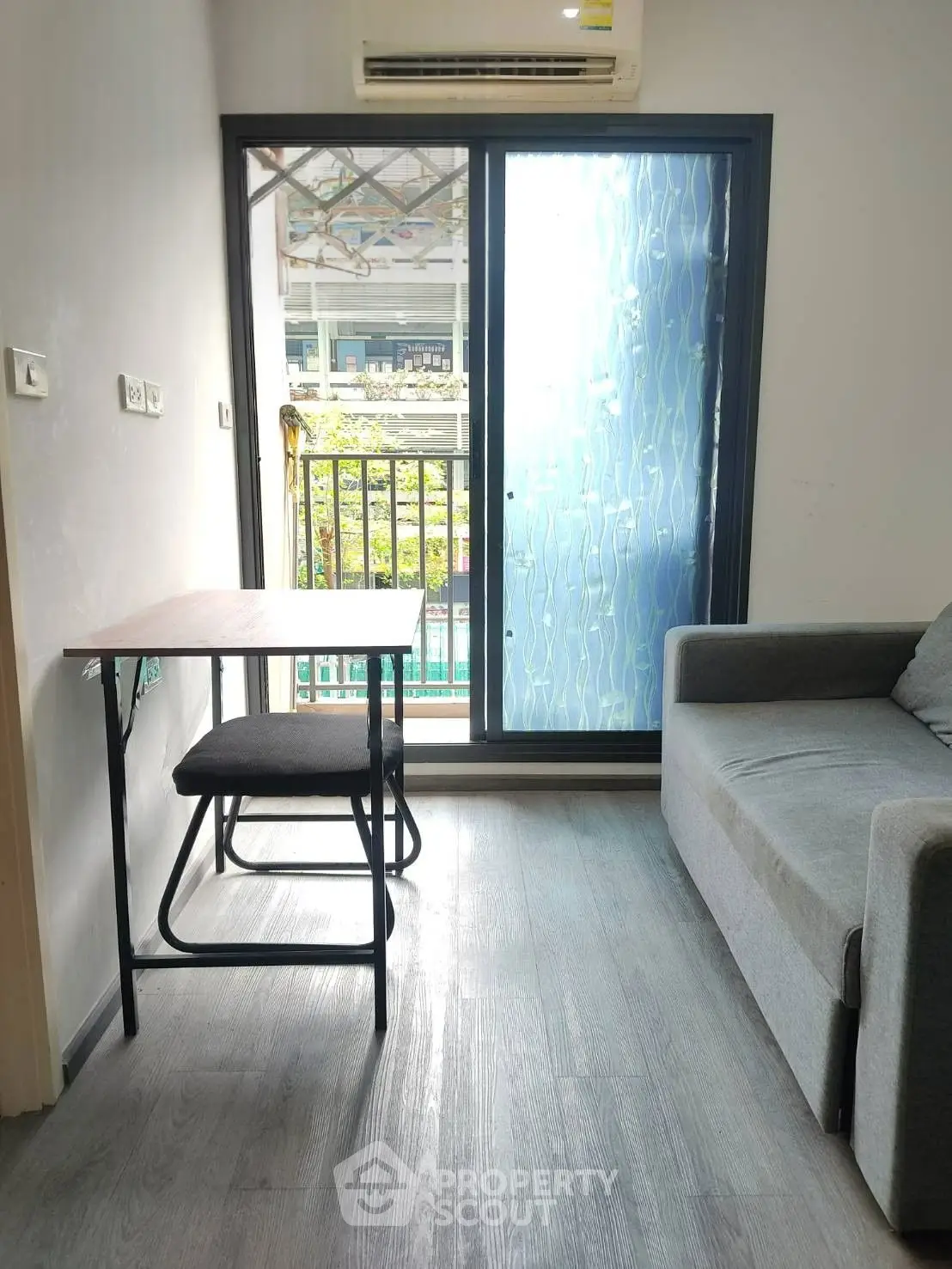 Cozy living room with modern sofa and balcony view, perfect for urban living.