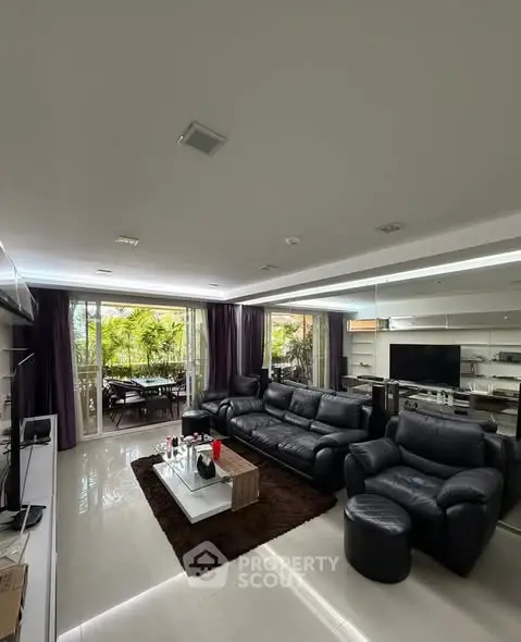 Luxurious living room with leather sofas and garden view, perfect for relaxation and entertainment.