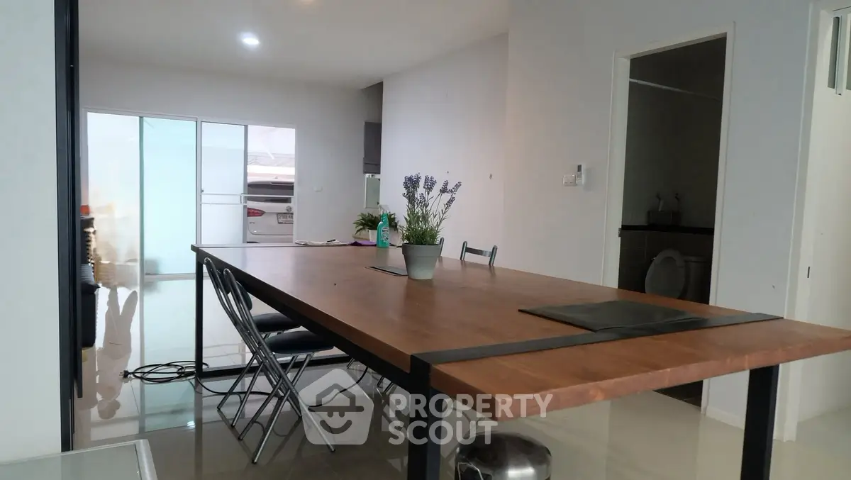 Spacious dining area with modern table and chairs, adjacent to a sleek kitchen with ample natural light.
