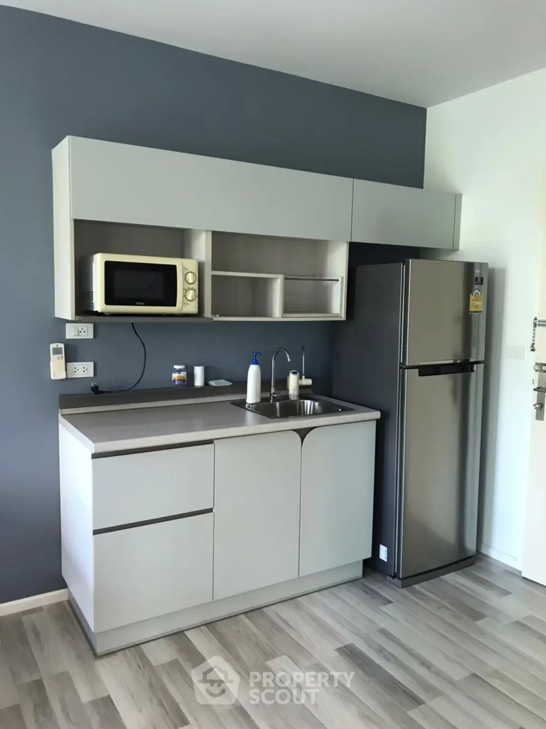 Modern compact kitchen with sleek cabinetry and stainless steel fridge