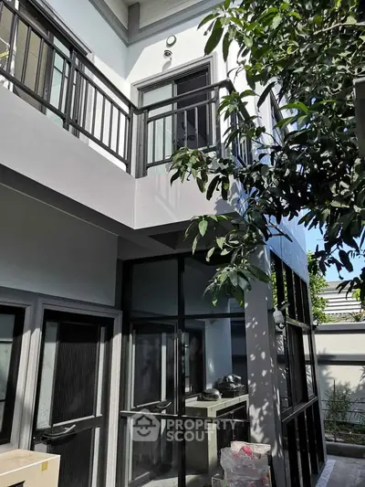 Modern two-story home exterior with sleek balcony and lush greenery