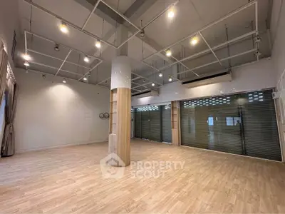 Spacious commercial space with modern lighting and wooden flooring, ideal for retail or office use.