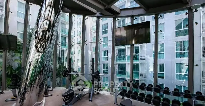 Modern gym with floor-to-ceiling windows offering stunning city views and state-of-the-art equipment.