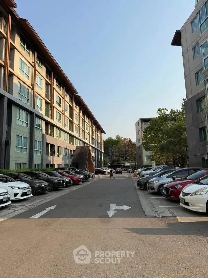 Modern apartment complex with spacious parking area and lush greenery.