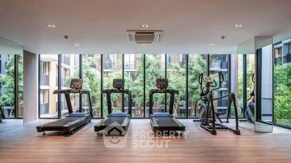 Modern gym with treadmills and large windows offering a scenic view of greenery.
