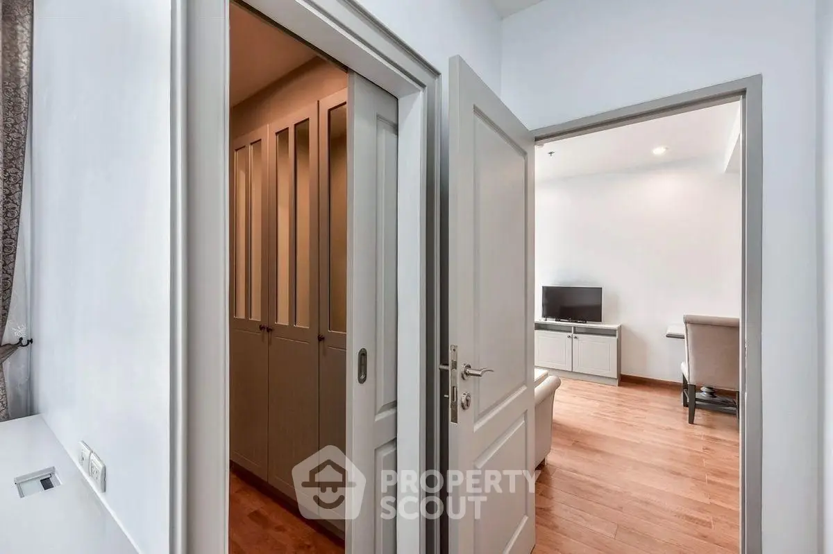 Modern apartment interior with open doors revealing living room and storage area.