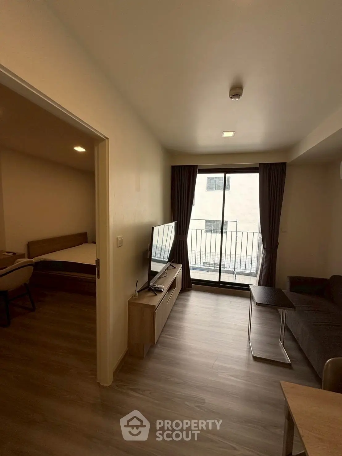 Modern living room with balcony access and sleek furnishings in a cozy apartment.
