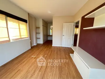 Spacious room with wooden flooring and built-in shelves, perfect for modern living.