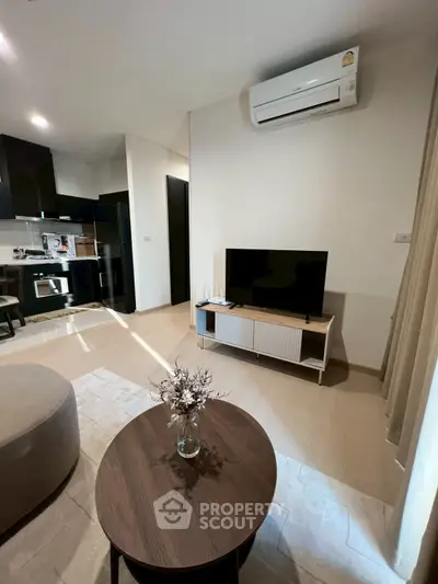 Modern living room with sleek furniture and open kitchen layout, featuring air conditioning and stylish decor.