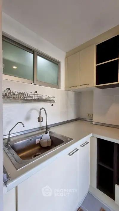 Compact kitchen with stainless steel sink and open shelving