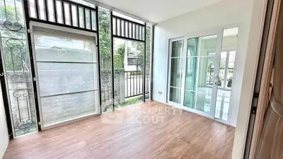 Bright room with large windows and wooden flooring, perfect for a cozy living space.