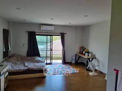 Spacious bedroom with balcony access and natural light, featuring modern decor and wooden flooring.