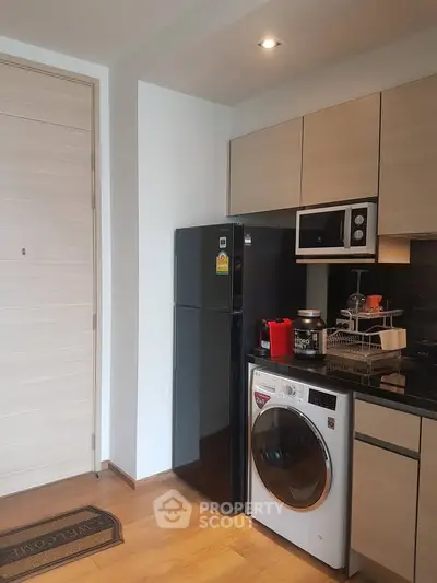 Modern kitchen with sleek appliances and wooden cabinetry in a stylish apartment.