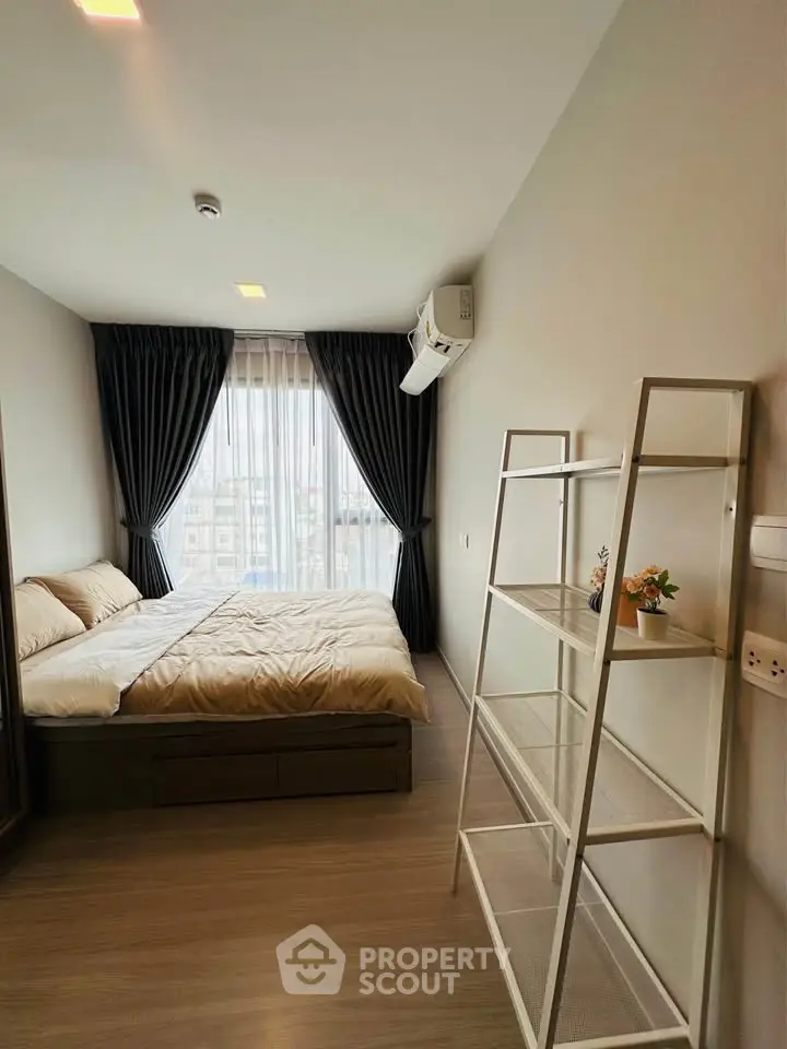 Modern bedroom with large window and stylish shelving unit, featuring elegant curtains and cozy bedding.