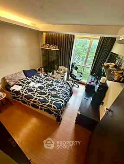 Spacious bedroom with large window and modern decor, offering a serene view.