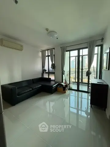 Modern living room with sleek black sofa and large windows offering city views