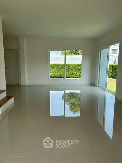 Spacious living room with glossy tiled floor and large windows overlooking garden.