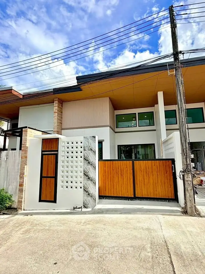 Modern townhouse exterior with stylish wooden gate and contemporary design.