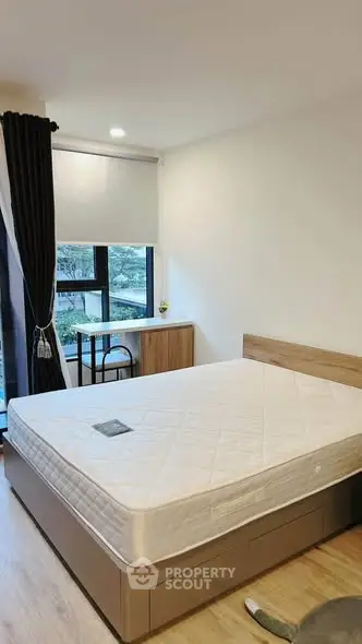 Cozy bedroom with large window and modern furnishings, perfect for relaxation and comfort.