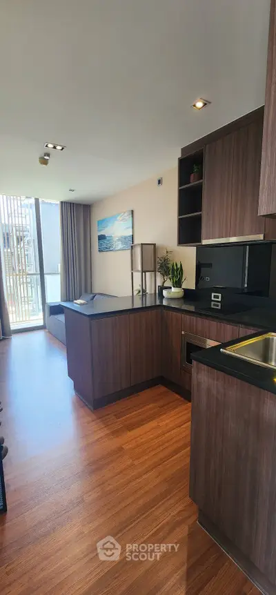 Modern kitchen with sleek wooden cabinetry and open layout, featuring a bright window view.
