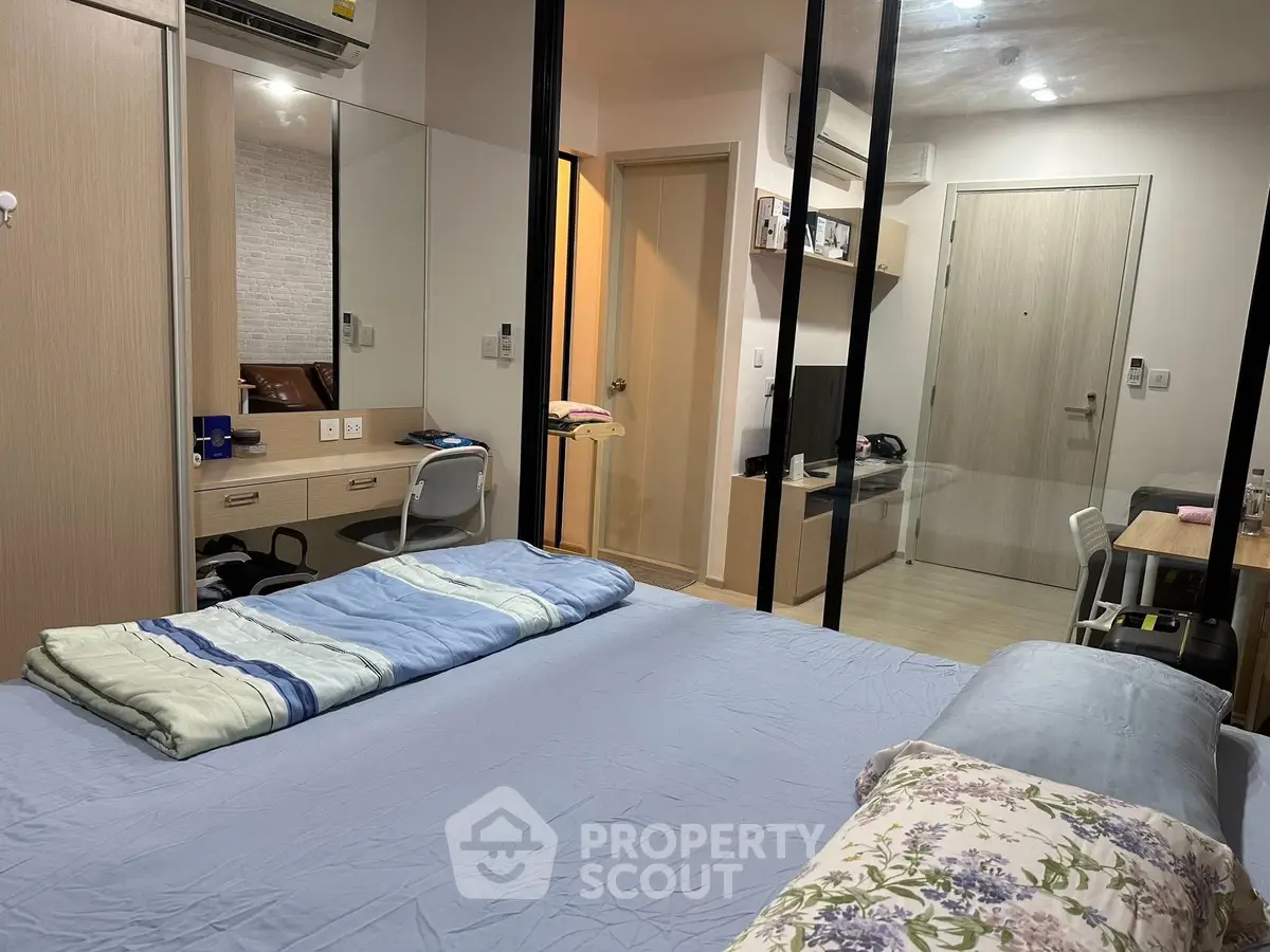 Cozy bedroom with modern decor, mirrored wardrobe, and compact workspace.