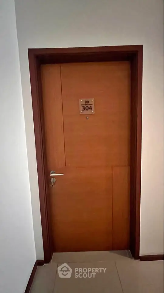 Modern apartment door with room number 304, showcasing sleek wooden design and secure lock.