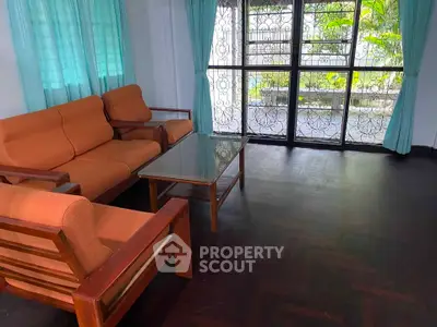 Spacious living room with orange sofa set and large window view.