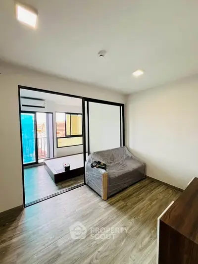 Modern living room with sliding glass doors and wooden flooring, featuring a cozy sofa and natural light.
