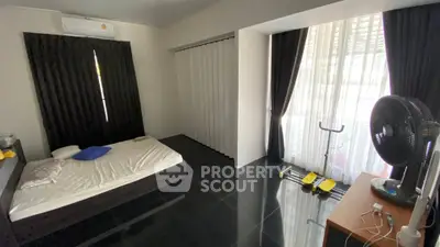 Spacious bedroom with modern decor and exercise equipment, featuring large windows and sleek flooring.