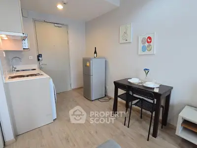 Cozy studio apartment with compact kitchen and dining area, featuring modern decor and wooden flooring.
