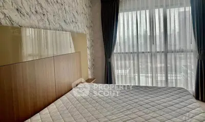 Modern bedroom with stylish decor and large window offering natural light.