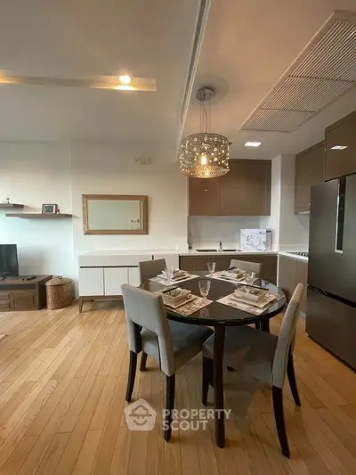 Modern dining area with elegant table setting in open kitchen layout, featuring sleek cabinetry and hardwood floors.