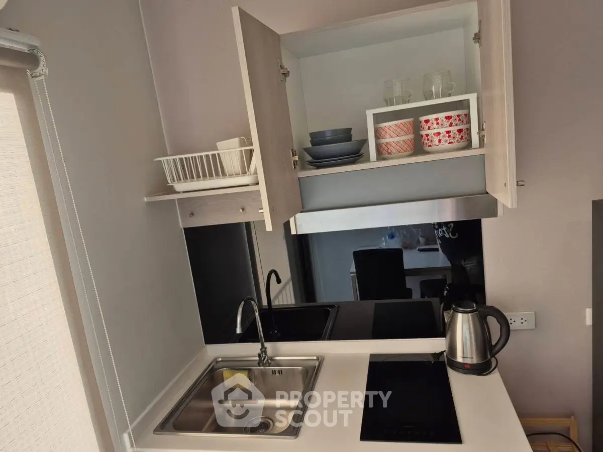 Modern compact kitchen with open cabinets, electric stove, and sleek sink design.