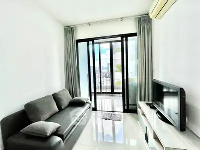 Modern living room with sleek sofa, TV, and balcony view in a bright apartment.