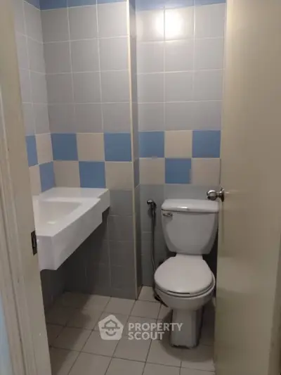 Compact bathroom with modern fixtures and tiled walls in a real estate property.