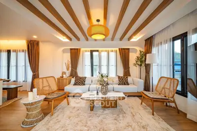 Luxurious living room with wooden beams, elegant furniture, and large windows offering natural light.