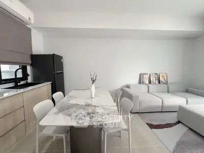 Modern open-plan kitchen and living room with sleek marble dining table and cozy gray sofa.