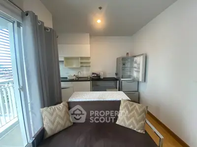 Modern apartment interior with open kitchen and cozy living area, featuring a balcony view.