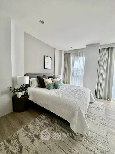 Modern bedroom with stylish decor and large windows offering natural light.