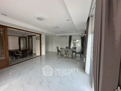 Spacious modern living room with elegant dining area and large windows.