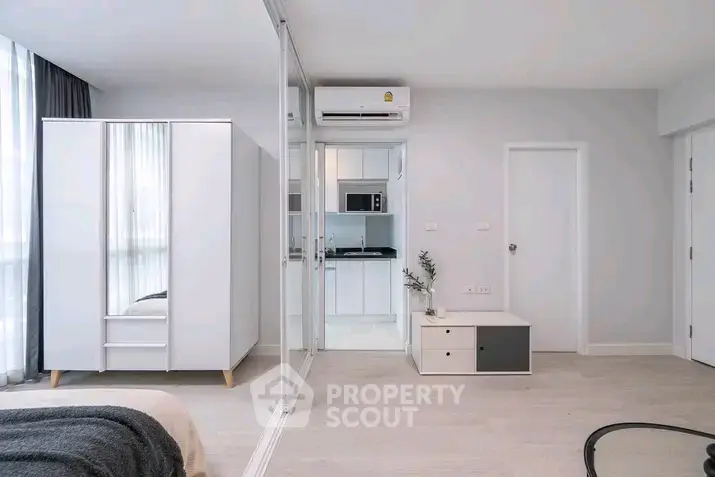 Modern minimalist bedroom with sleek wardrobe and compact kitchen area.