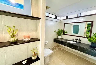 Spacious modern bathroom with elegant decor and large mirror, featuring stylish shelving and lush greenery.