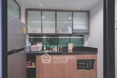 Modern kitchen with sleek cabinets and appliances, featuring a microwave and spacious fridge.