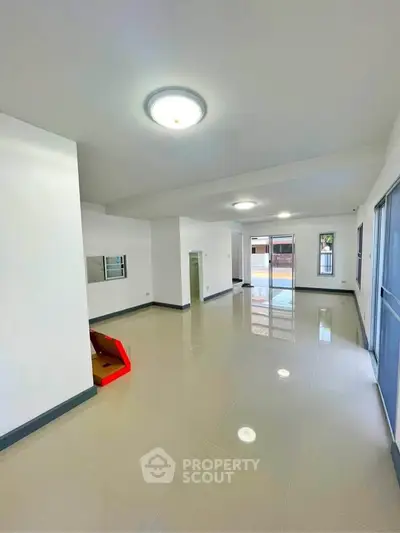 Spacious open-plan living area with glossy tiled floors and ample natural light.