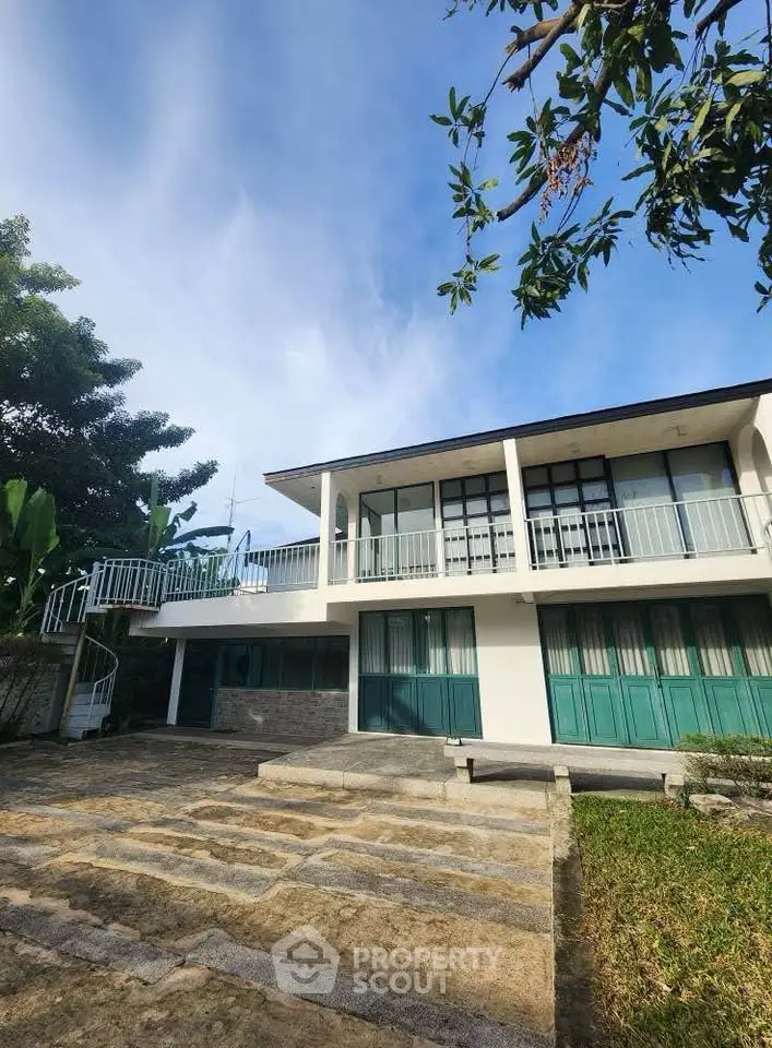 Stunning modern two-story home with spacious balcony and lush greenery