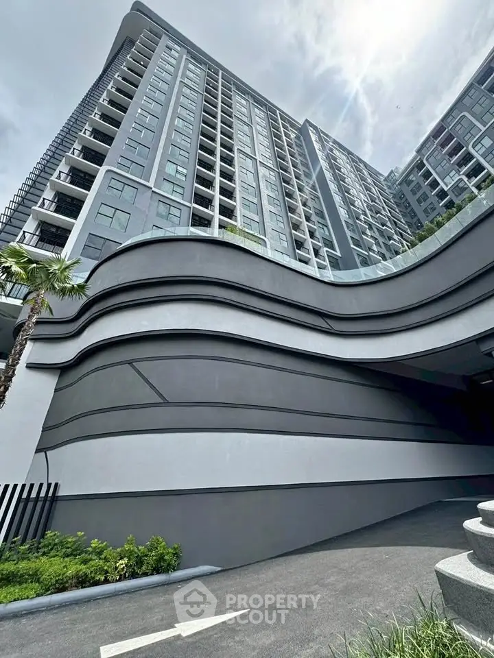 Modern high-rise building with sleek architectural design and lush greenery.